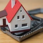 Mortgage scam concept depicted by a figure of a house inside a steel trap.