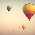 Hot air balloons up on a cloudy sky.