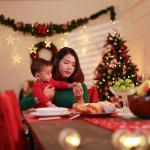 A young mother sitting alone with holding her baby at the dinner table during Christmas Eve.