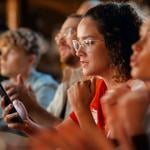 A female football fan in a bar monitoring game results on her phone.