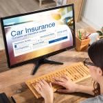 A businesswoman filling out a car insurance form using a desktop.