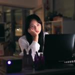 A tired female employee working overtime in the office at night.