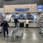 Customers picking up items at a pharmacy counter.