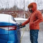 A man charging his EV during a snowy day.