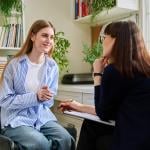 A female teenage patient talking to a mental health therapist.
