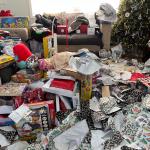 Piles of messy packaging and opened presents in a living room during Christmas morning.