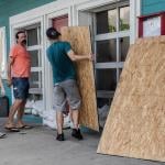 A group of workers board restaurant windows in preparation for a hurricane.