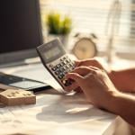 A real estate professional using a calculator over tax documents.