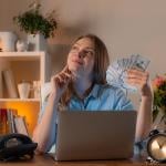 A female manager holding cash daydreaming in an office.