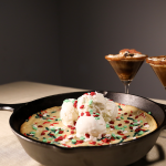A 'Winter Wonderland' Sugar Cookie on a skillet with two glasses of Gingerbread Espresso Martini.