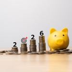 2026 target savings represented by a yellow piggy bank and a row of stacked coins.