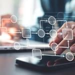 Person using a laptop and phone illustrated with automated business workflow chart graphics.