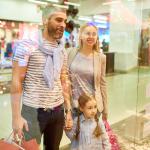A happy family looking at window displays while shopping at a mall.