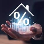 A real estate agent's hand holding up a hologram of a home with percentage figure.
