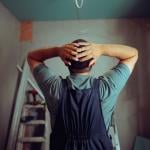 Back view of a construction worker with hands on head as he notices mistakes in a project.