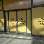 Entrance of a new retail store with 'opening soon' signs.
