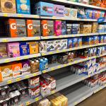 Shelves stocked with protein bars in a grocery store.