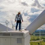 A windmill engineer on top of a wind turbine for inspection.