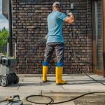 A pressure wash cleaner working on a dirty brick wall.