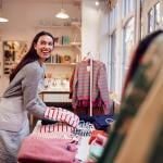 A female business owner arranging stock clothing for her store's window display.
