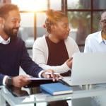 Three members of a business team brainstorming on strategy in an office.