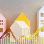 Colorful wooden figures of homes illustrated with finance chart graphics.