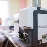 A focus on a microwave plasma atomic emission spectrometer (MPAES) a scientist is working with in a laboratory.