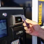 Hand of a person paying using card by the fuel pump at a gas station.