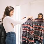 A young woman looking at a winter sweater in a dressing room.