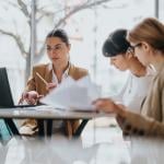 A group of three female professionals in a coworking space.