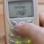 A retro Nokia 3410 mobile phone in someone's hand with the settings menu open.