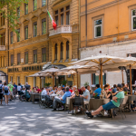 Tables under umbrellas filled with people outside of restaurants in Rome. 