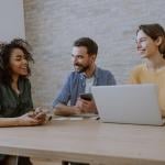 A 3-member creative team engaged together in a discussion in an office.