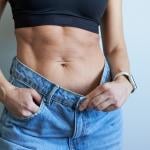 Close up on a woman's torso showing her jeans' gap in size after weight loss.