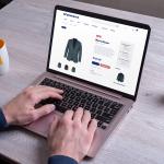Person using a laptop to shop for men's blazer online.