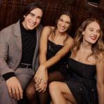 A group of three young personalities happily posing and sitting on an events sofa during a holiday celebration.
