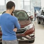 Rear view of a man choosing a car at a dealership.