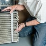 Man changing a folded dirty air filter of an HVAC system.