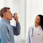 A female doctor monitoring her senior patient in taking an asthma inhaler.