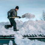 Young person shoveling heavy snow on a rooftop.