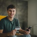 A happy young man using a credit card to purchase online.