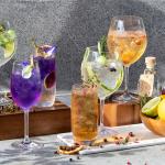 A display of assorted homemade herbal cocktails in wine glasses.