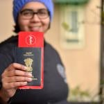 Portrait of a young Indian woman holding up her passport with an international flight ticket.