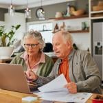 A senior couple using a laptop to review documents.