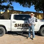 Sheriff Brad Coe of Kinney County, Texas, stands in front of his white truck, he is is one of hundreds of sheriffs who have signed on to collaborate with U.S. Customs and Border Enforcement (ICE) under the rapidly expanding Section 287(g) program.