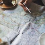 Person tracing a map with a pen for travel planning.