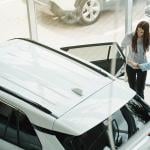 A young couple checking out a car at a dealership.