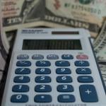 A calculator with a background of US dollar banknotes.