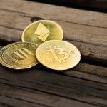 Gold crypto coins on a wooden surface.