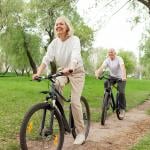 A senior couple riding bikes in a park.